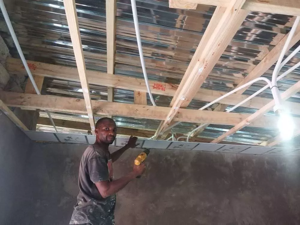 Construction worker installing ceiling tiles