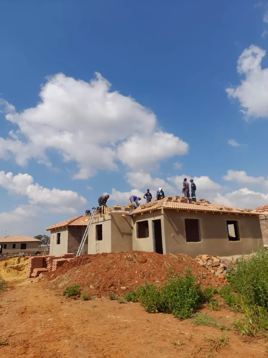 Construction workers roofing a house under a clear blue sky