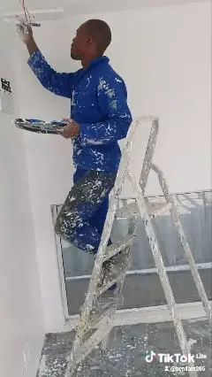 Painter on a stepladder painting an interior wall
