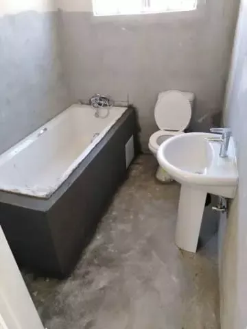 Unfinished bathroom interior with bathtub, toilet, and sink