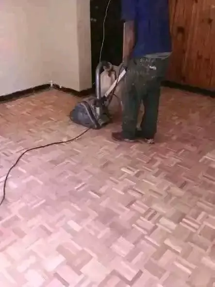 Worker using a floor sanding machine on a parquet wooden floor