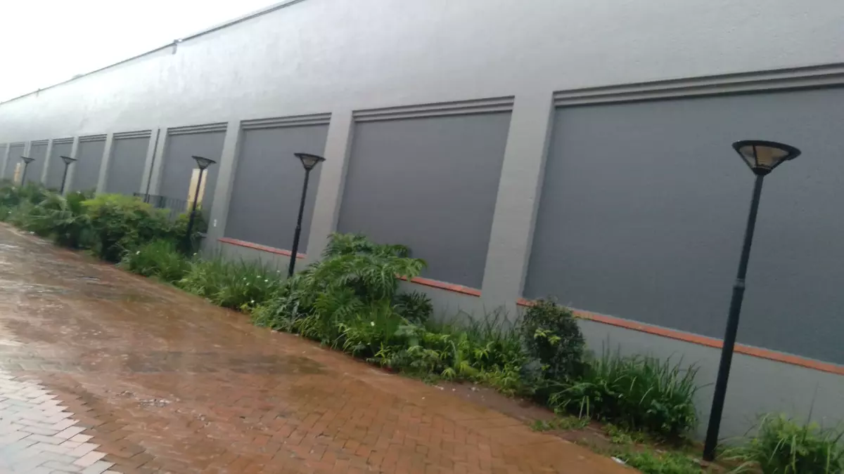 Modern building exterior wall with recessed dark panels and brick walkway