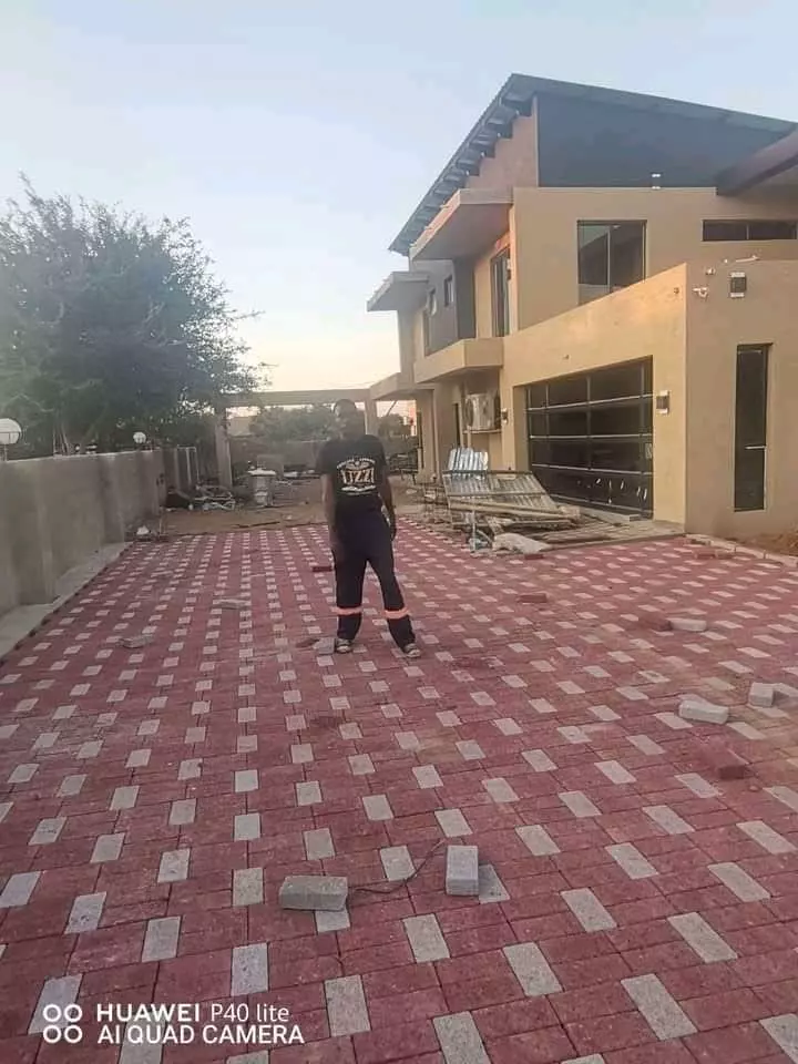 A man standing on a newly paved brick driveway in front of a modern house