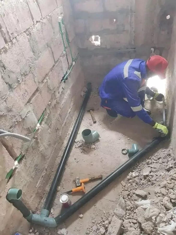 Construction worker installing plumbing pipes in an unfinished room