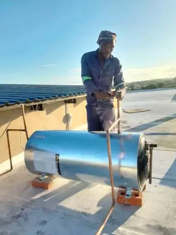 Worker installing a water heater on a rooftop