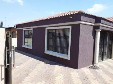Modern single-story house exterior with purple-brown walls and tiled roof