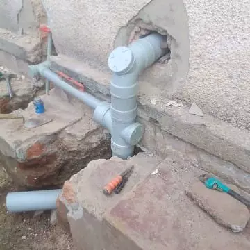 Grey PVC plumbing pipes installed against a rough concrete wall