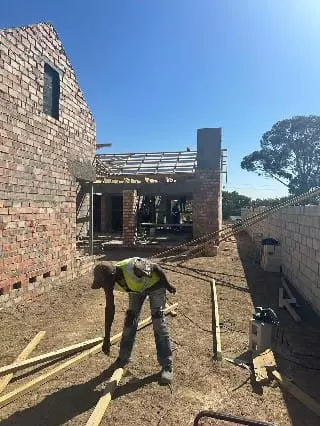 Construction site with a worker and partially built brick house