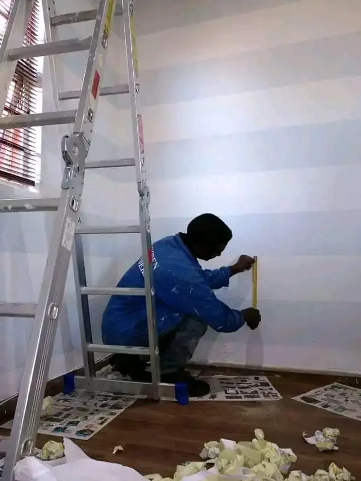 Painter measuring striped wall