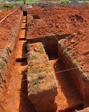 Foundation trenches dug in red soil for construction